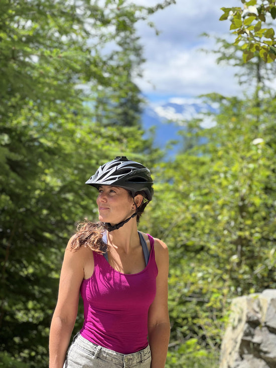 Woman wearing a bike helmet looking out to the mountains she is about to ride on her bike in Squamish, BC