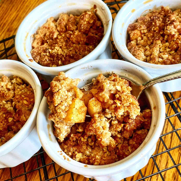 Four bowls of Fierce Fuel Apple Crumble, a comforting and convenient apple crumble dessert, neatly arranged on a cooling rack.