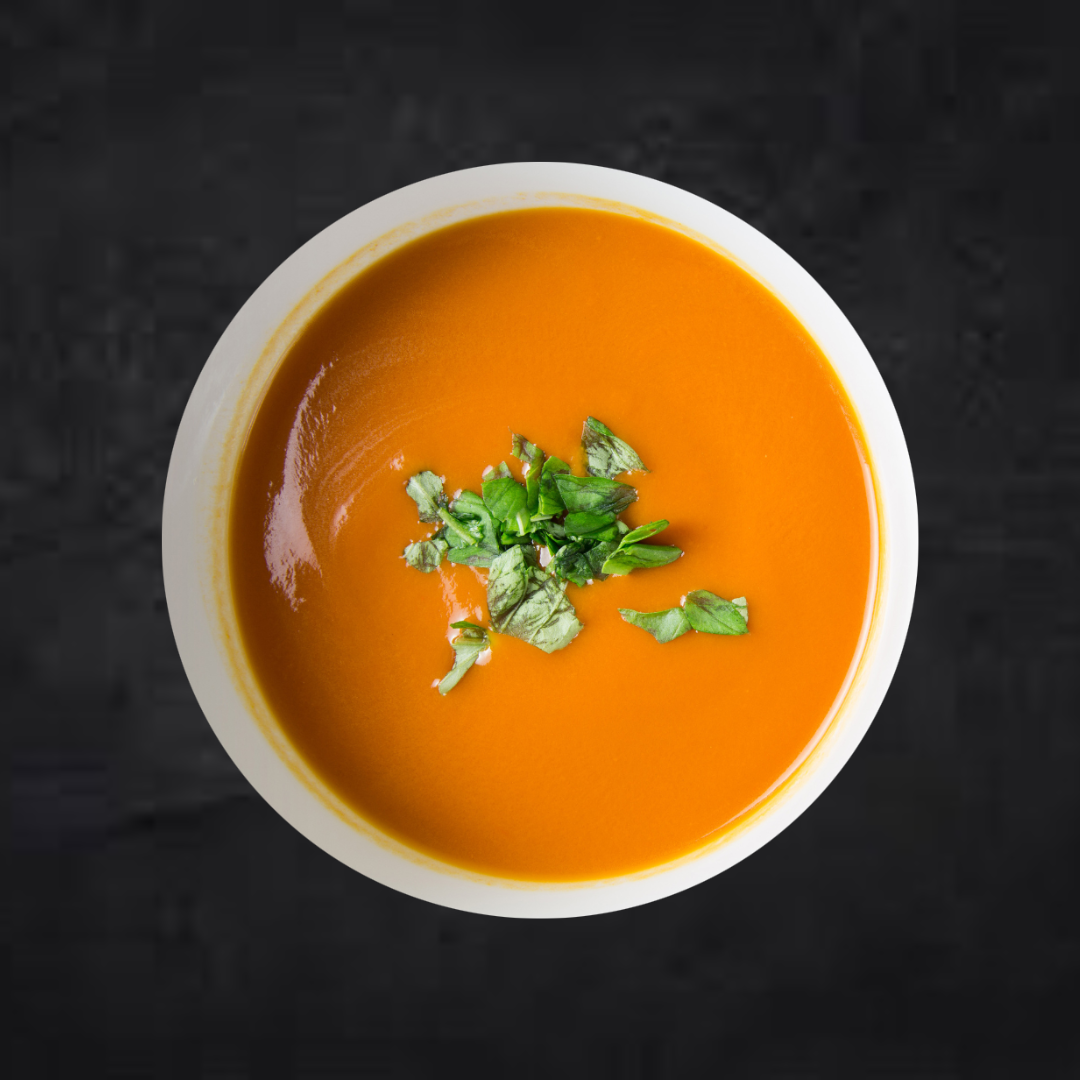 A bowl of healthy Roasted Root Veggie Soup by Fierce Fuel on a black background.