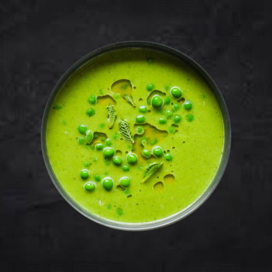 A bowl of Fierce Fuel Pea & Mint Soup with sprigs of thyme perfect for prepped meals.